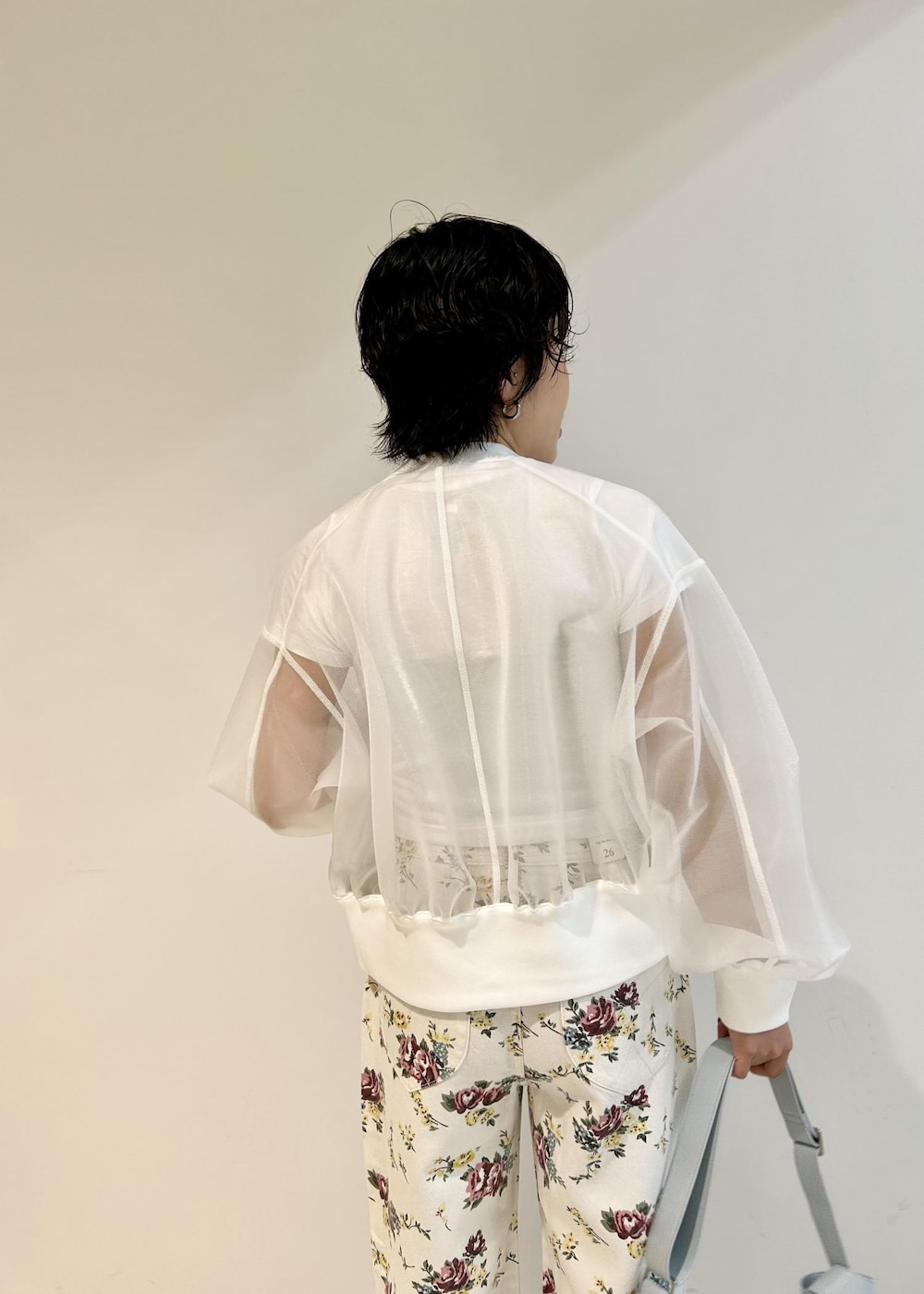 ブルー系のショルダーバッグ、ホワイト系のカーディガン/ボレロ、ベージュ系のデニムパンツを着用したレディースの春コーディネートの5枚目の写真