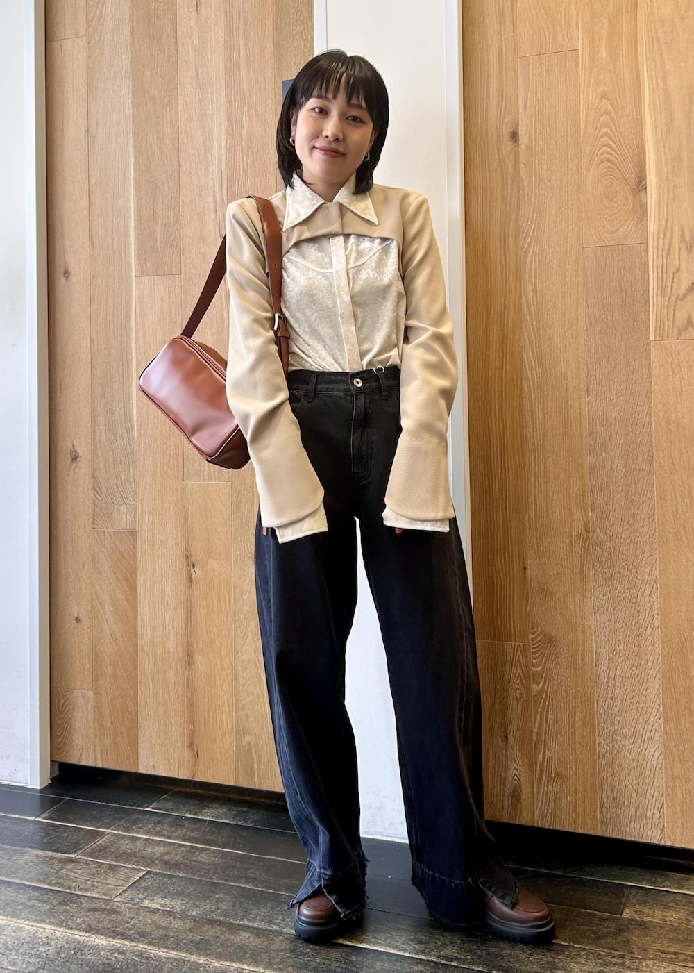 ブラック系のデニムパンツ、ブラウン系のショルダーバッグ、ブラウン系のローファーを着用したレディースの秋コーディネートの2枚目の写真