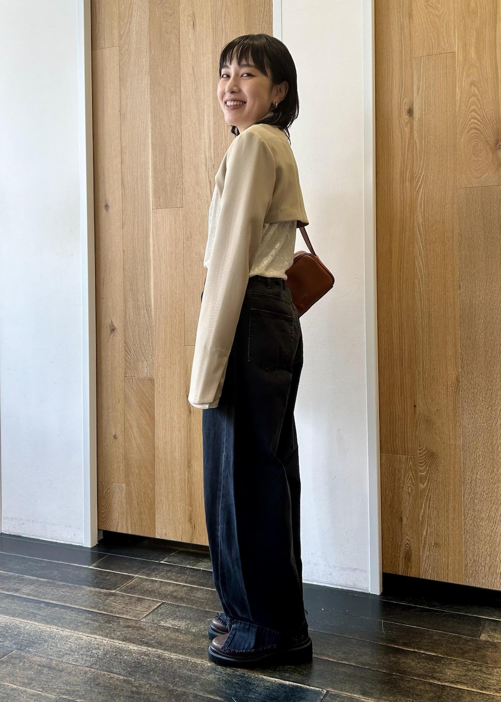 ブラック系のデニムパンツ、ブラウン系のショルダーバッグ、ブラウン系のローファーを着用したレディースの秋コーディネートの3枚目の写真