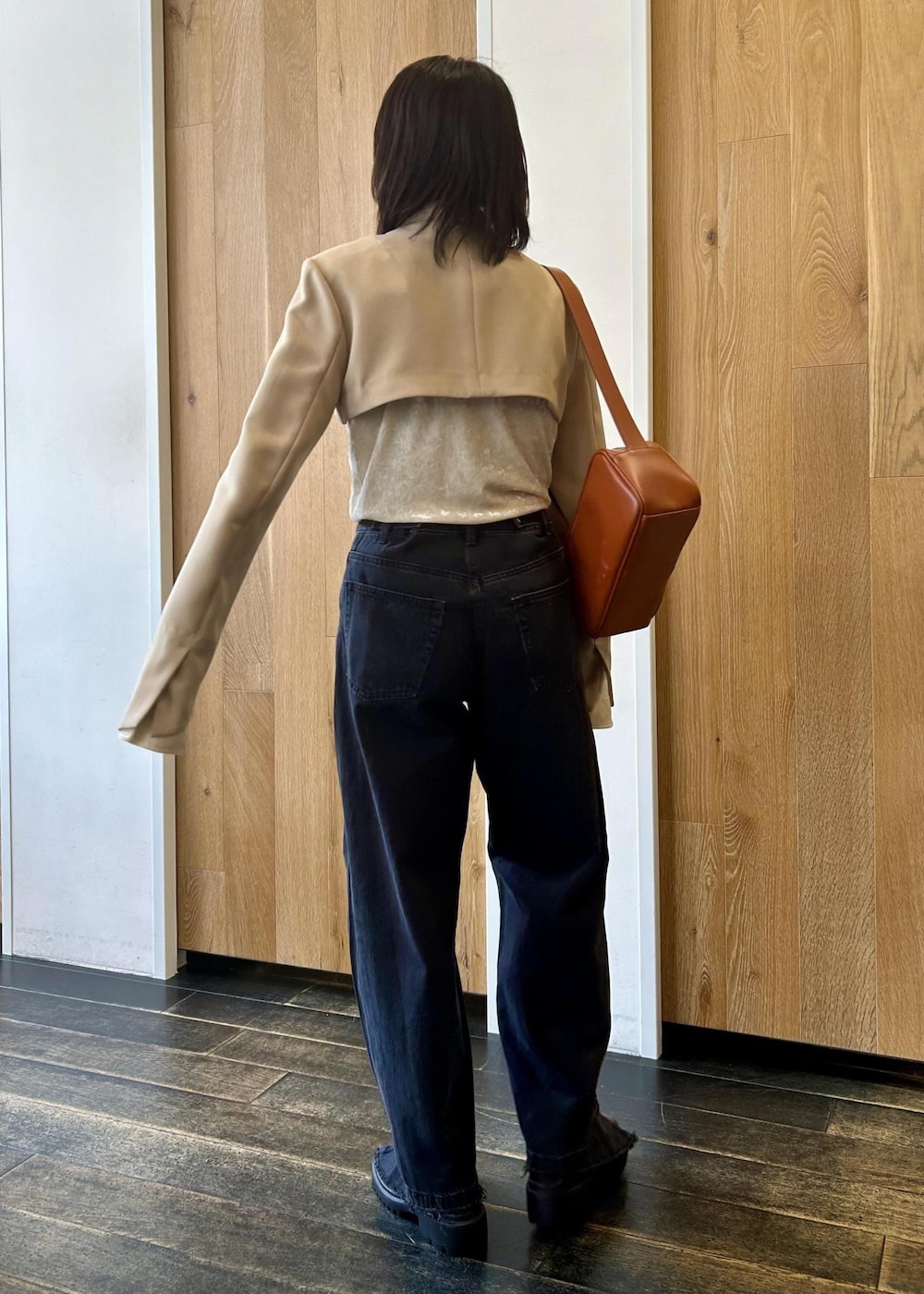 ブラック系のデニムパンツ、ブラウン系のショルダーバッグ、ブラウン系のローファーを着用したレディースの秋コーディネートの4枚目の写真