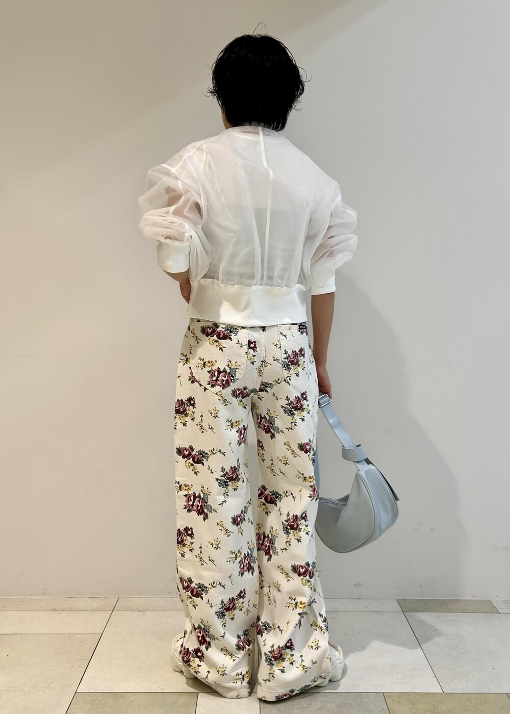 ブルー系のショルダーバッグ、ホワイト系のカーディガン/ボレロ、ベージュ系のデニムパンツを着用したレディースの春コーディネートの3枚目の写真