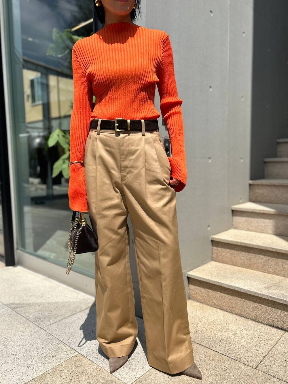 ベージュ系のチノパンツ、オレンジ系のニット/セーター、ブラウン系のベルトを着用したレディースの夏コーディネートの9枚目の写真
