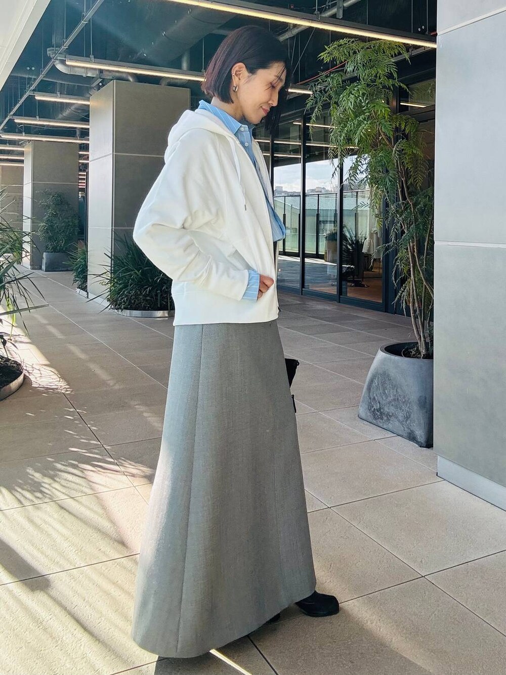 ホワイト系のパーカー、グレー系のスカートを着用したレディースの冬コーディネートの2枚目の写真