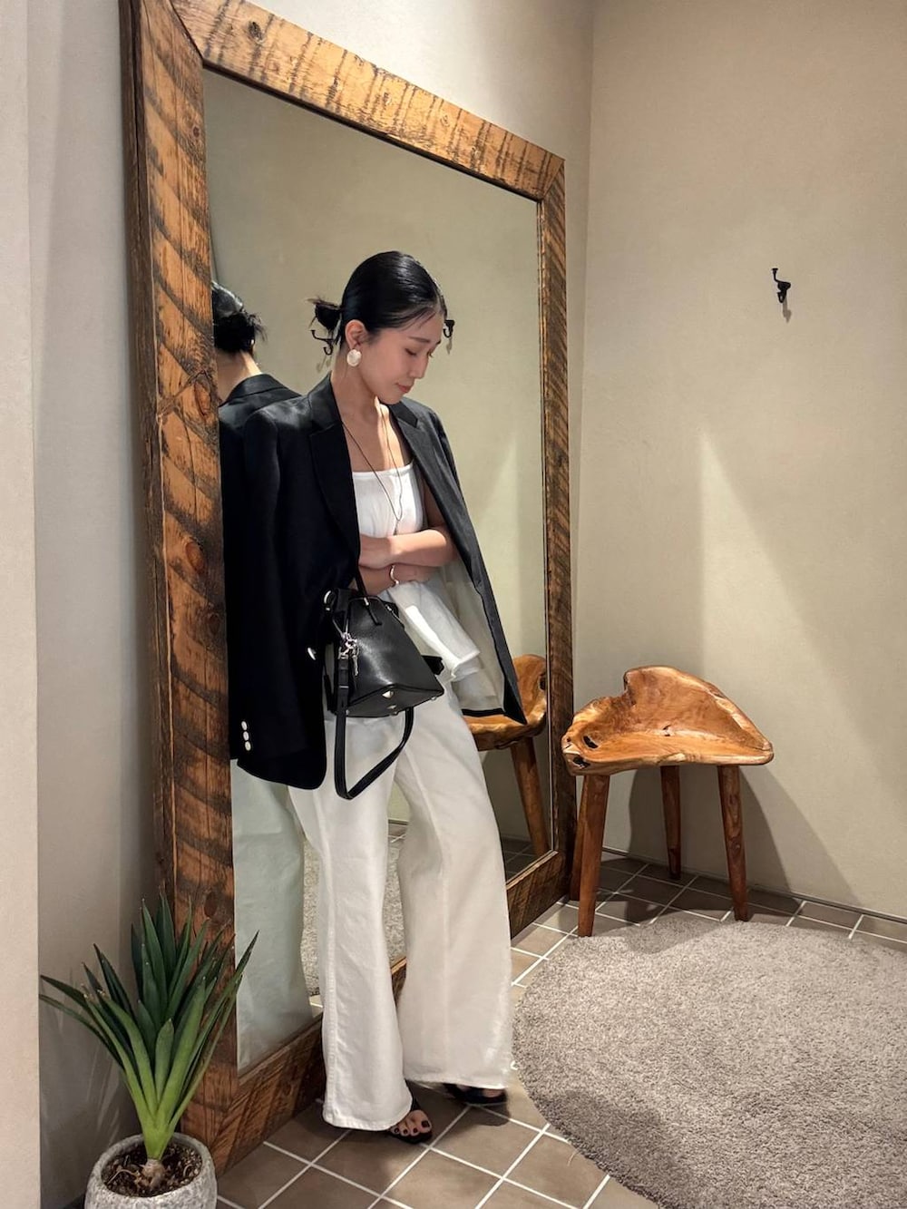 ホワイト系のデニムパンツ、ブラック系のテーラードジャケット、ホワイト系のキャミソールを着用したレディースの春コーディネートの7枚目の写真