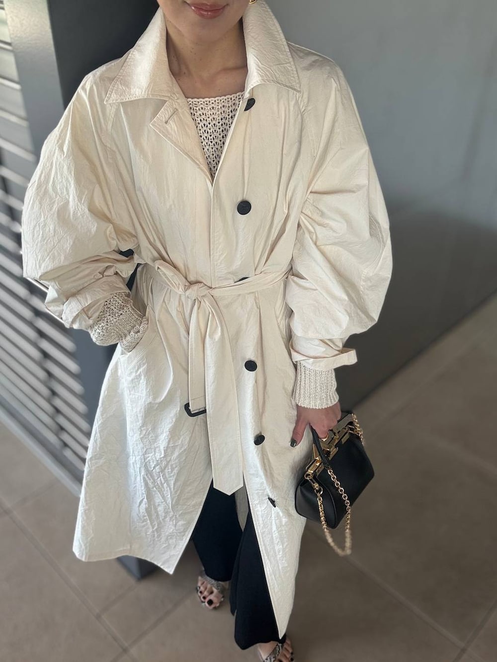 ホワイト系のニット/セーター、ブラック系のその他パンツ、ホワイト系のステンカラーコートを着用したレディースの春コーディネートの6枚目の写真