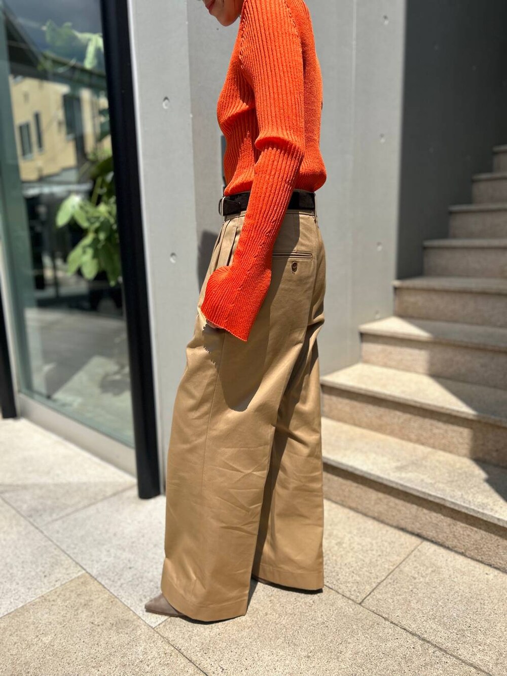 ベージュ系のチノパンツ、オレンジ系のニット/セーター、ブラウン系のベルトを着用したレディースの夏コーディネートの8枚目の写真