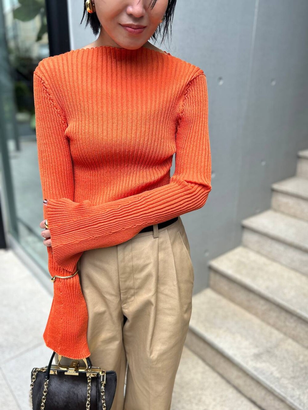 ベージュ系のチノパンツ、オレンジ系のニット/セーター、ブラウン系のベルトを着用したレディースの夏コーディネートの4枚目の写真