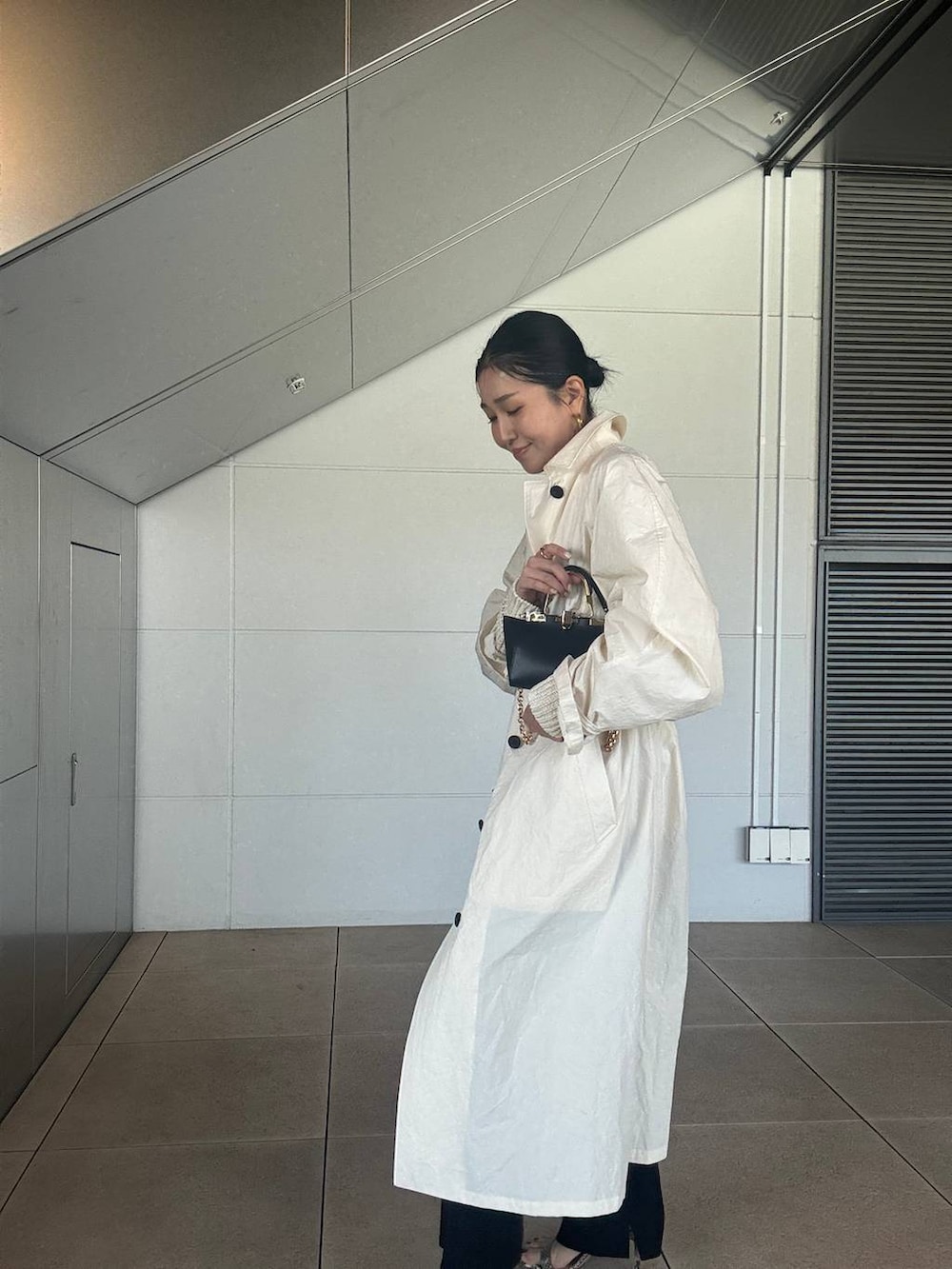 ホワイト系のニット/セーター、ブラック系のその他パンツ、ホワイト系のステンカラーコートを着用したレディースの春コーディネートの3枚目の写真