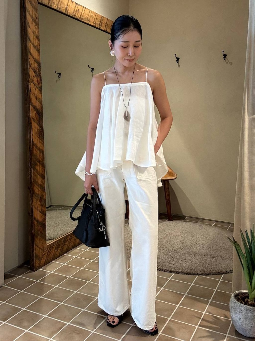 ホワイト系のデニムパンツ、ブラック系のテーラードジャケット、ホワイト系のキャミソールを着用したレディースの春コーディネートの4枚目の写真