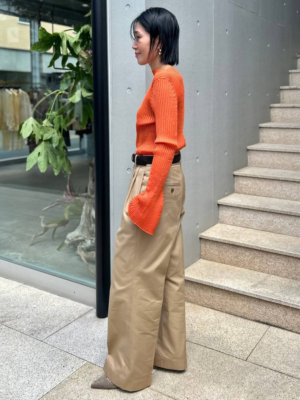 ベージュ系のチノパンツ、オレンジ系のニット/セーター、ブラウン系のベルトを着用したレディースの夏コーディネートの2枚目の写真