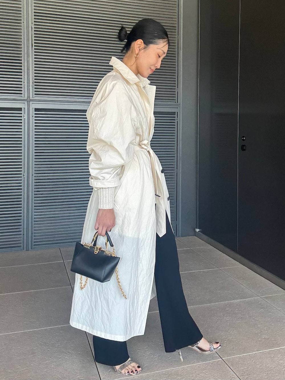 ホワイト系のニット/セーター、ブラック系のその他パンツ、ホワイト系のステンカラーコートを着用したレディースの春コーディネートの2枚目の写真