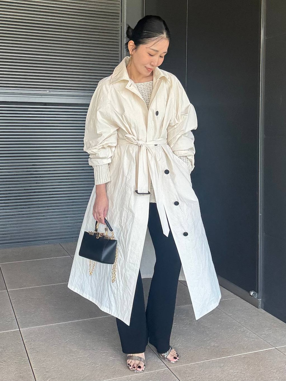 ホワイト系のニット/セーター、ブラック系のその他パンツ、ホワイト系のステンカラーコートを着用したレディースの春コーディネートの7枚目の写真