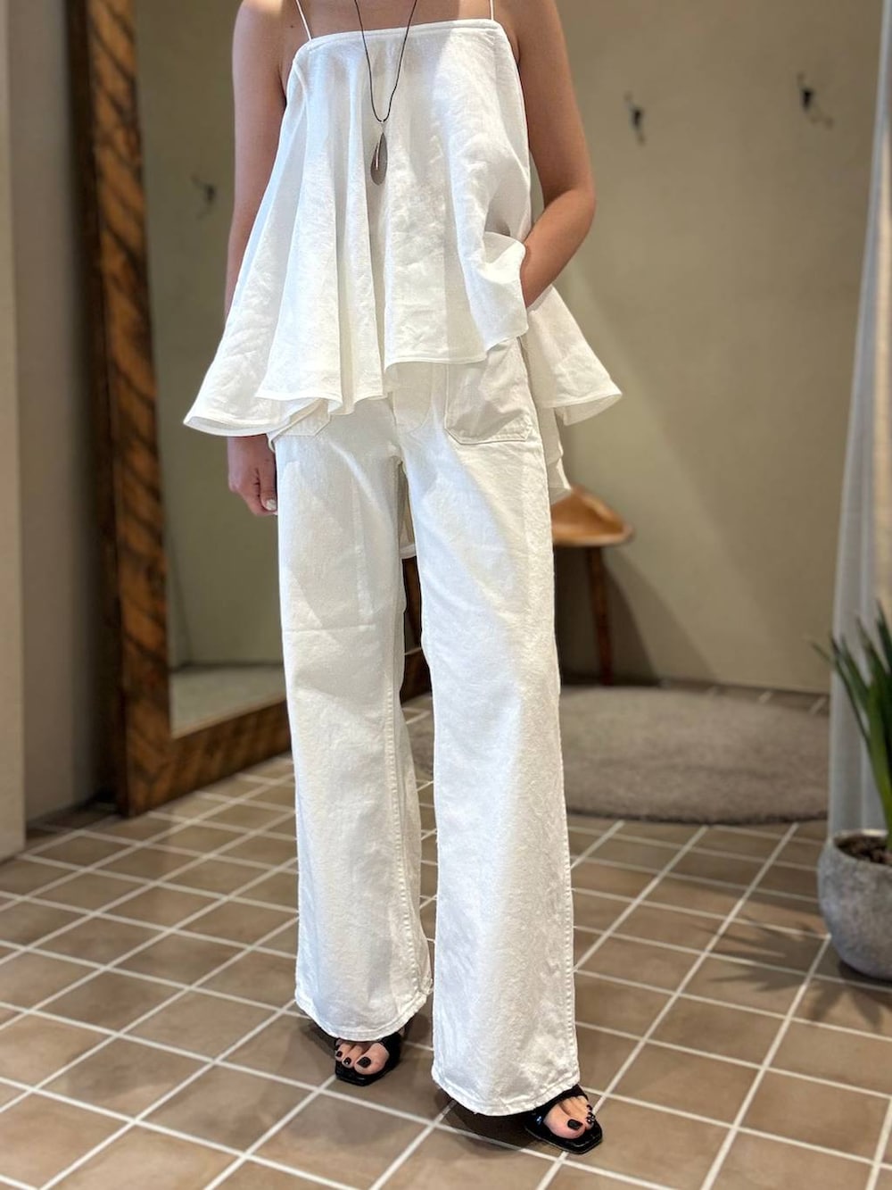 ホワイト系のデニムパンツ、ブラック系のテーラードジャケット、ホワイト系のキャミソールを着用したレディースの春コーディネートの6枚目の写真