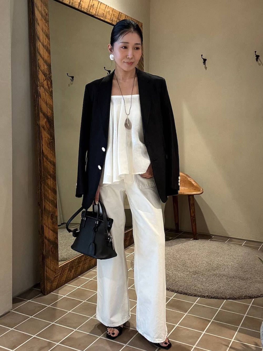 ホワイト系のデニムパンツ、ブラック系のテーラードジャケット、ホワイト系のキャミソールを着用したレディースの春コーディネートの2枚目の写真