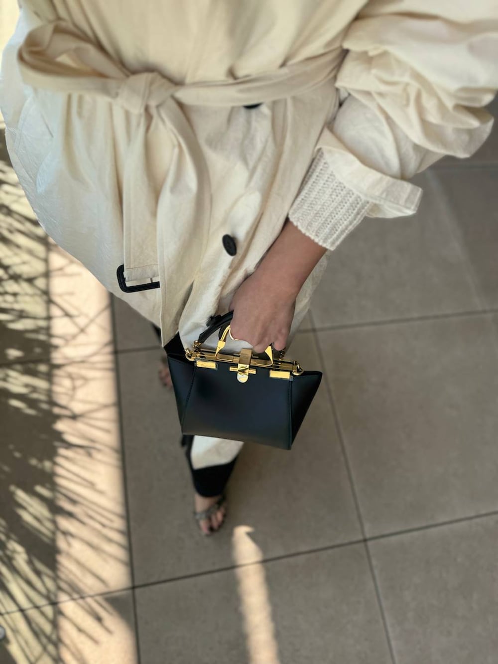 ホワイト系のニット/セーター、ブラック系のその他パンツ、ホワイト系のステンカラーコートを着用したレディースの春コーディネートの5枚目の写真