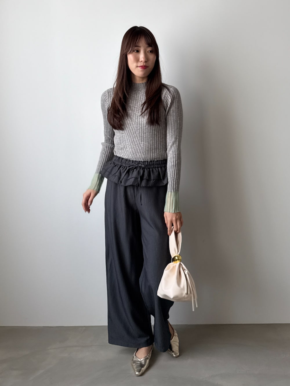 グレー系のニット/セーター、ブラック系のその他パンツを着用したレディースの秋コーディネートの2枚目の写真