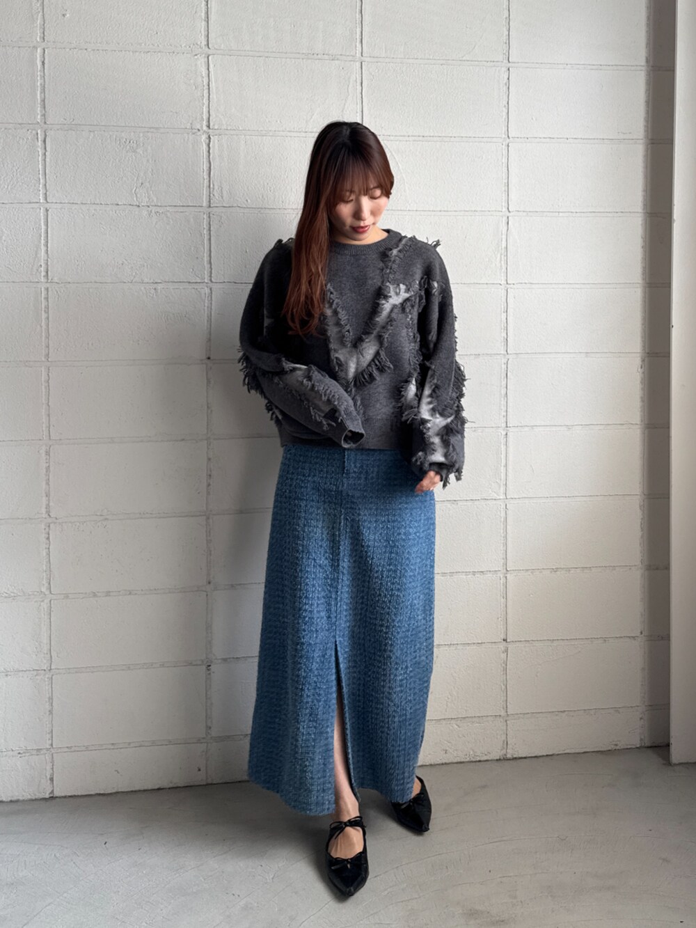 グレー系のニット/セーター、ブルー系のデニムスカートを着用したレディースの秋コーディネートの2枚目の写真