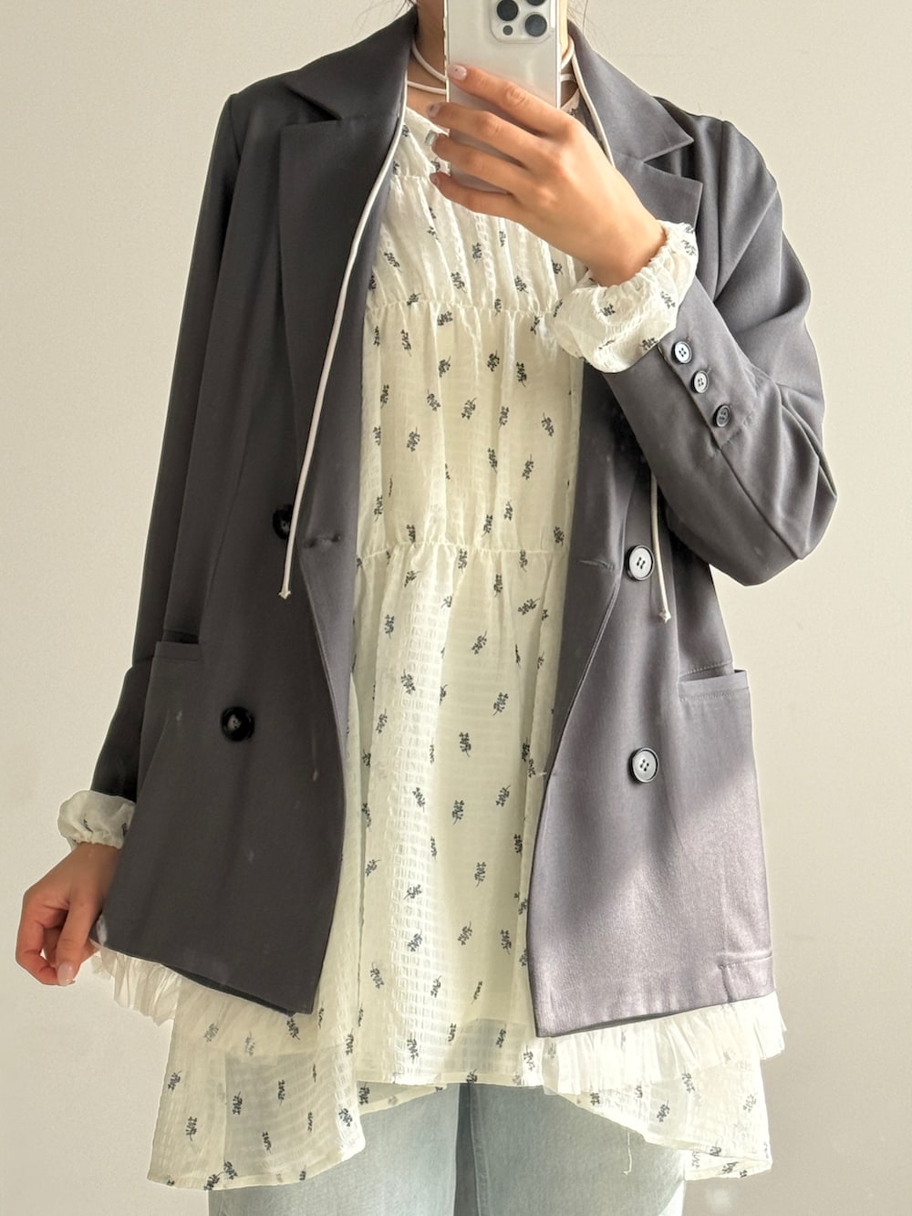 ホワイト系のワンピース、グレー系のテーラードジャケット、ブルー系のデニムパンツを着用したレディースの春コーディネートの2枚目の写真