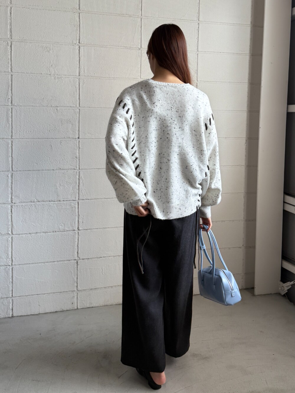 グレー系のニット/セーター、ブルー系のボストンバッグ、ブラック系のその他パンツを着用したレディースの秋コーディネートの2枚目の写真