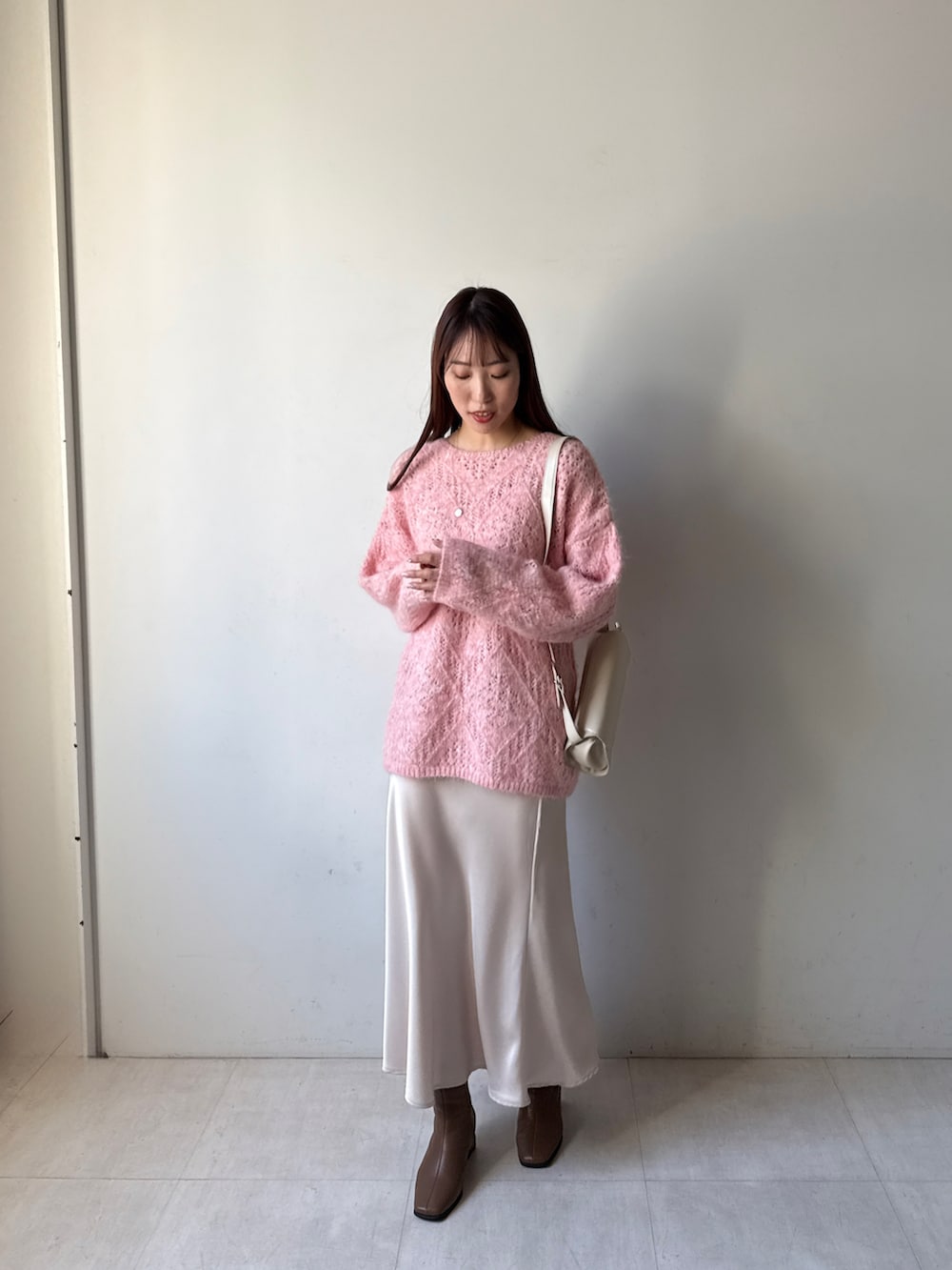 ピンク系のニット/セーター、ベージュ系のスカートを着用したレディースの秋コーディネートの2枚目の写真