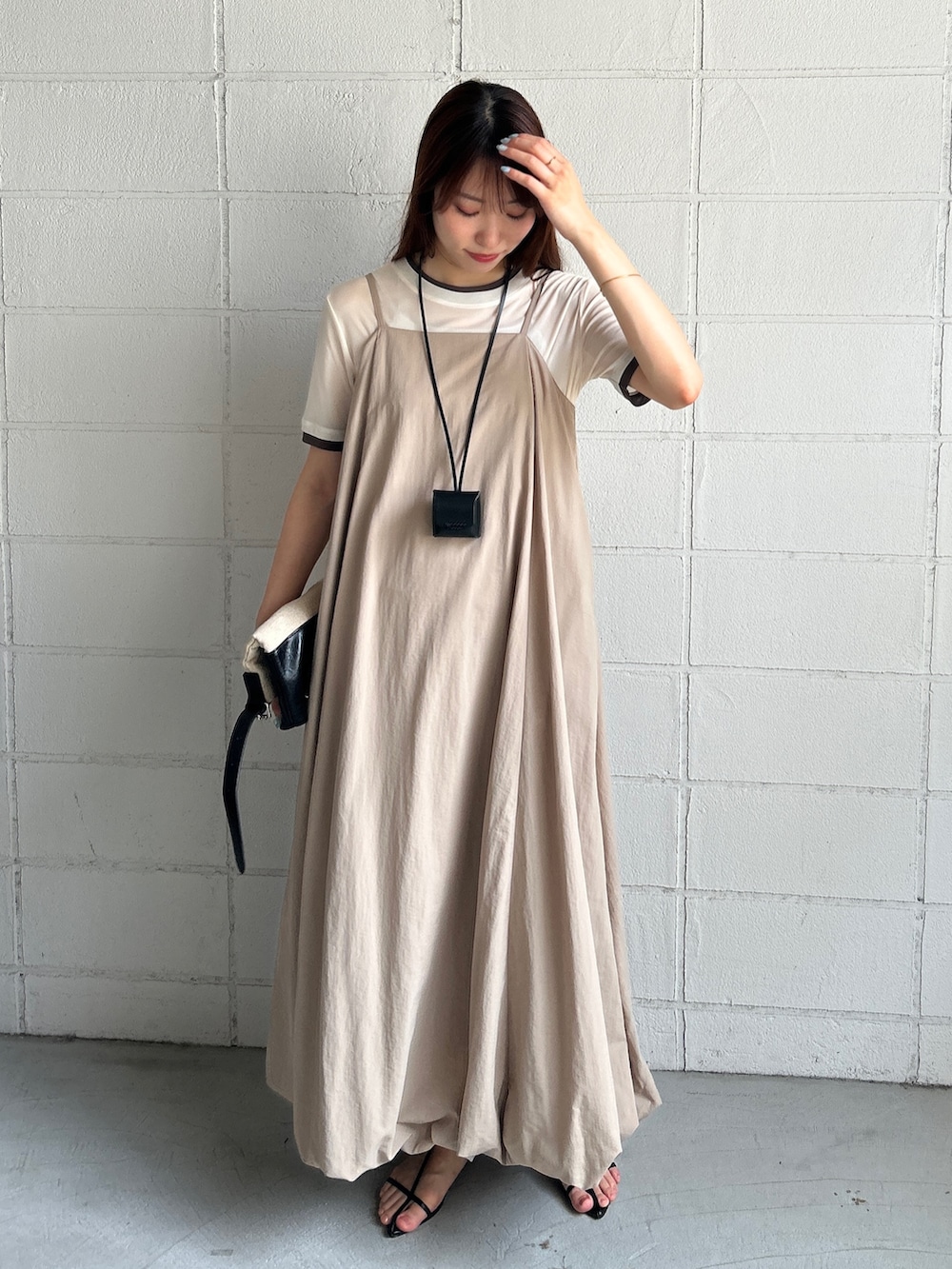 ベージュ系のワンピース、ホワイト系のTシャツ/カットソー、ベージュ系のショルダーバッグを着用したレディースの夏コーディネートの3枚目の写真