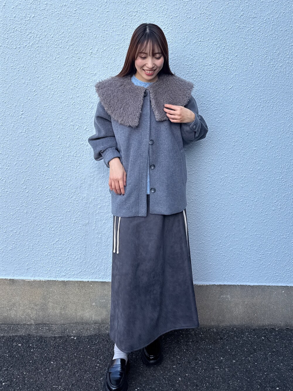 グレー系のダウンジャケット/コート、ブルー系のニット/セーター、グレー系のスカートを着用したレディースの秋コーディネートの2枚目の写真