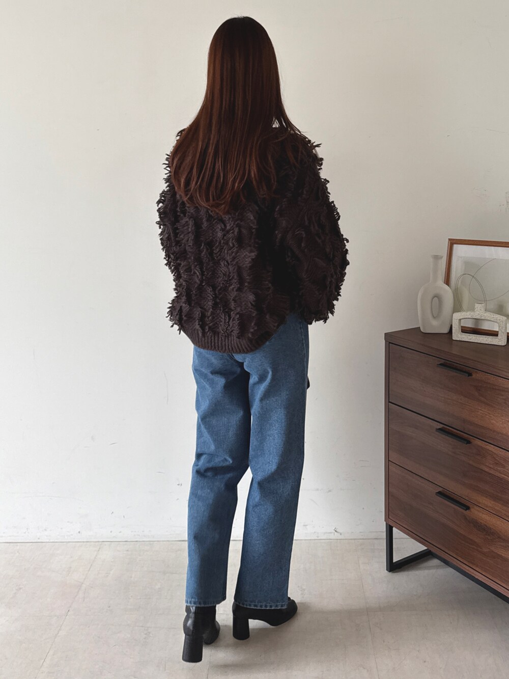 グレー系のニット/セーター、ブルー系のデニムパンツを着用したレディースの秋コーディネートの2枚目の写真