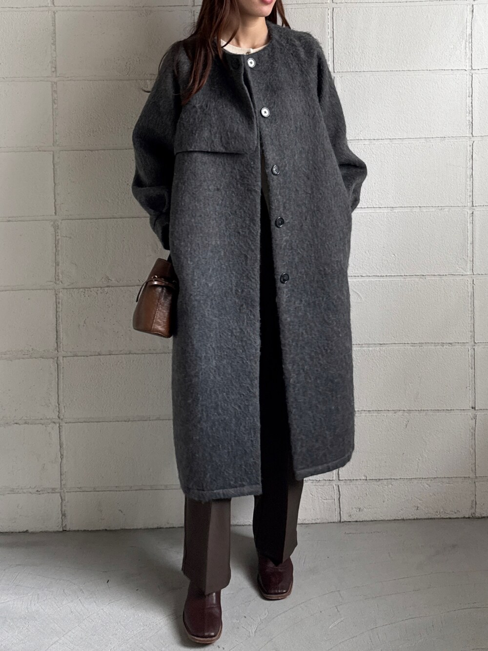 ブラウン系のショルダーバッグ、ブラウン系のスラックス、グレー系のノーカラーコートを着用したレディースの冬コーディネートの2枚目の写真