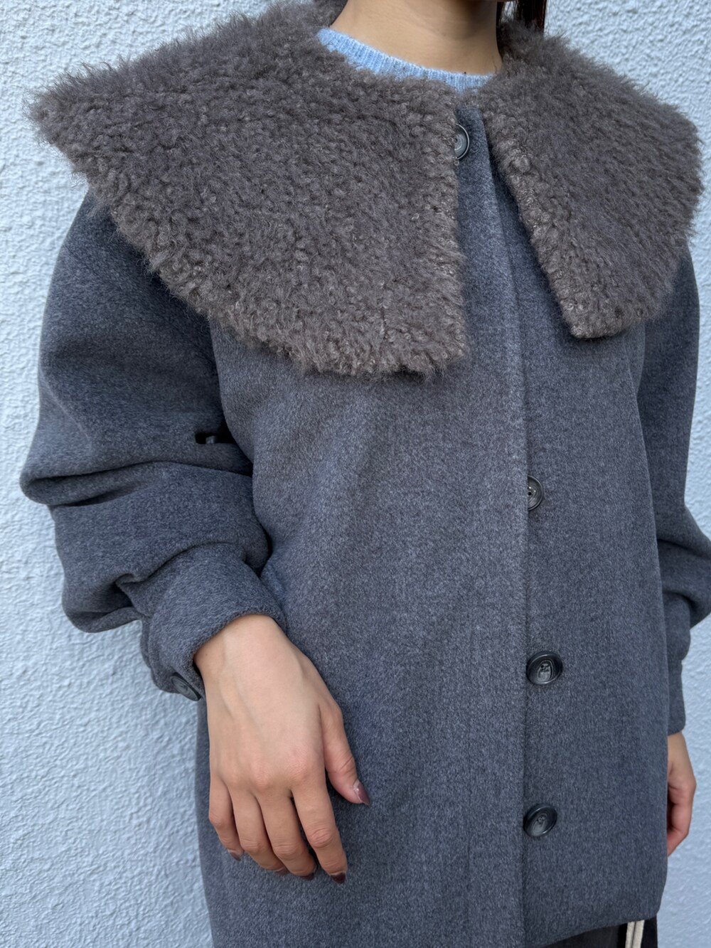 グレー系のダウンジャケット/コート、ブルー系のニット/セーター、グレー系のスカートを着用したレディースの秋コーディネートの4枚目の写真