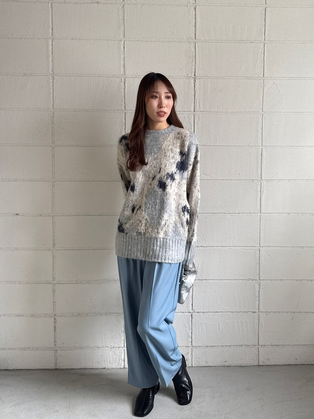 グレー系のニット/セーター、ブルー系のスラックスを着用したレディースの冬コーディネートの2枚目の写真