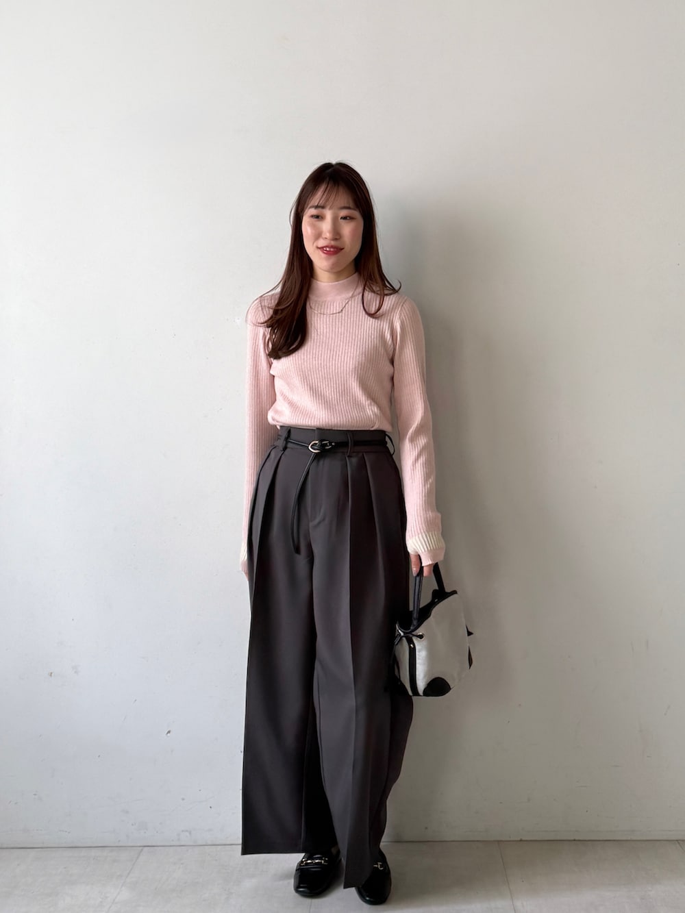 ピンク系のニット/セーター、グレー系のスラックスを着用したレディースの冬コーディネートの3枚目の写真