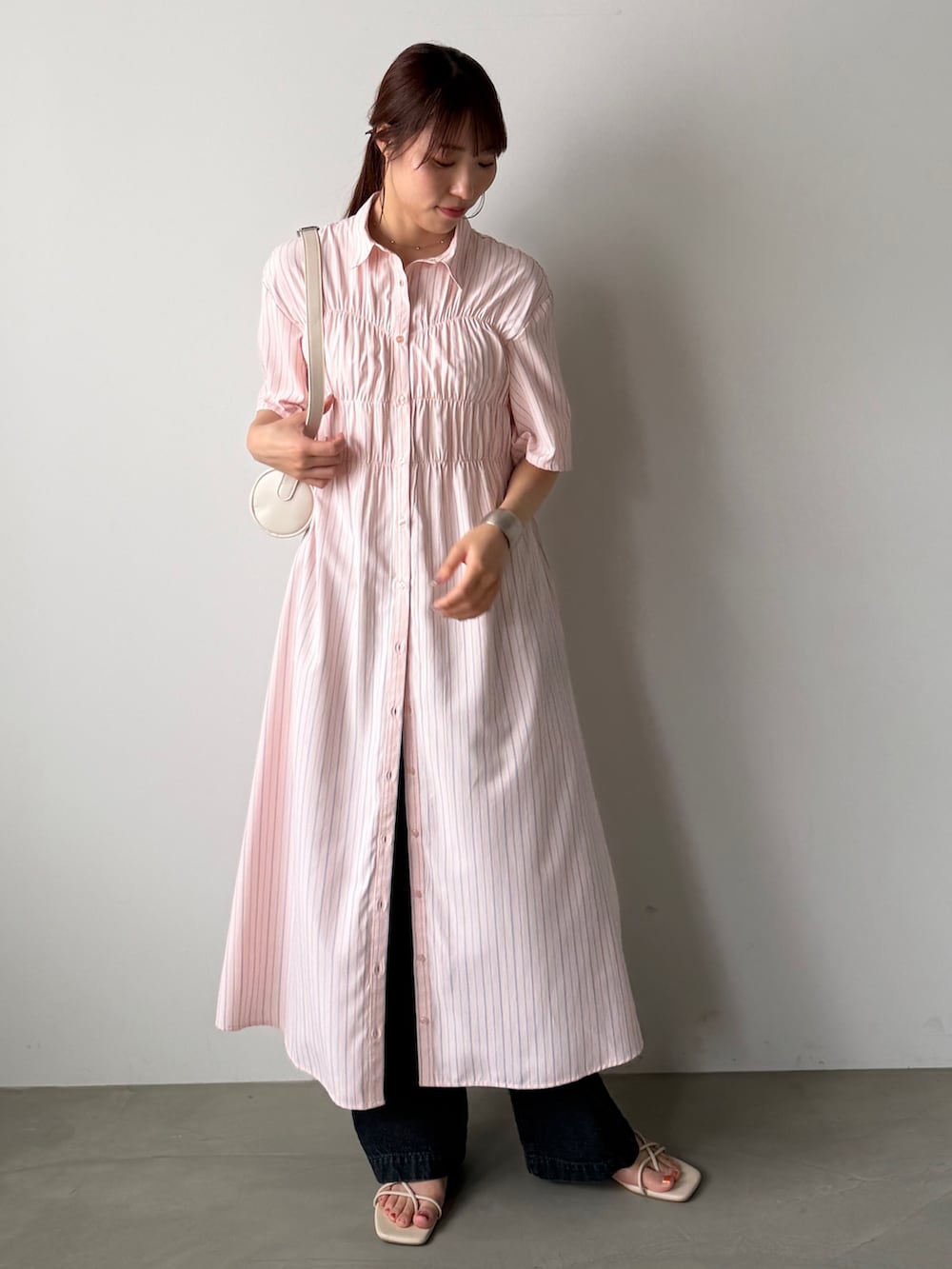 ピンク系のシャツワンピース、ホワイト系のショルダーバッグを着用したレディースの夏コーディネートの2枚目の写真