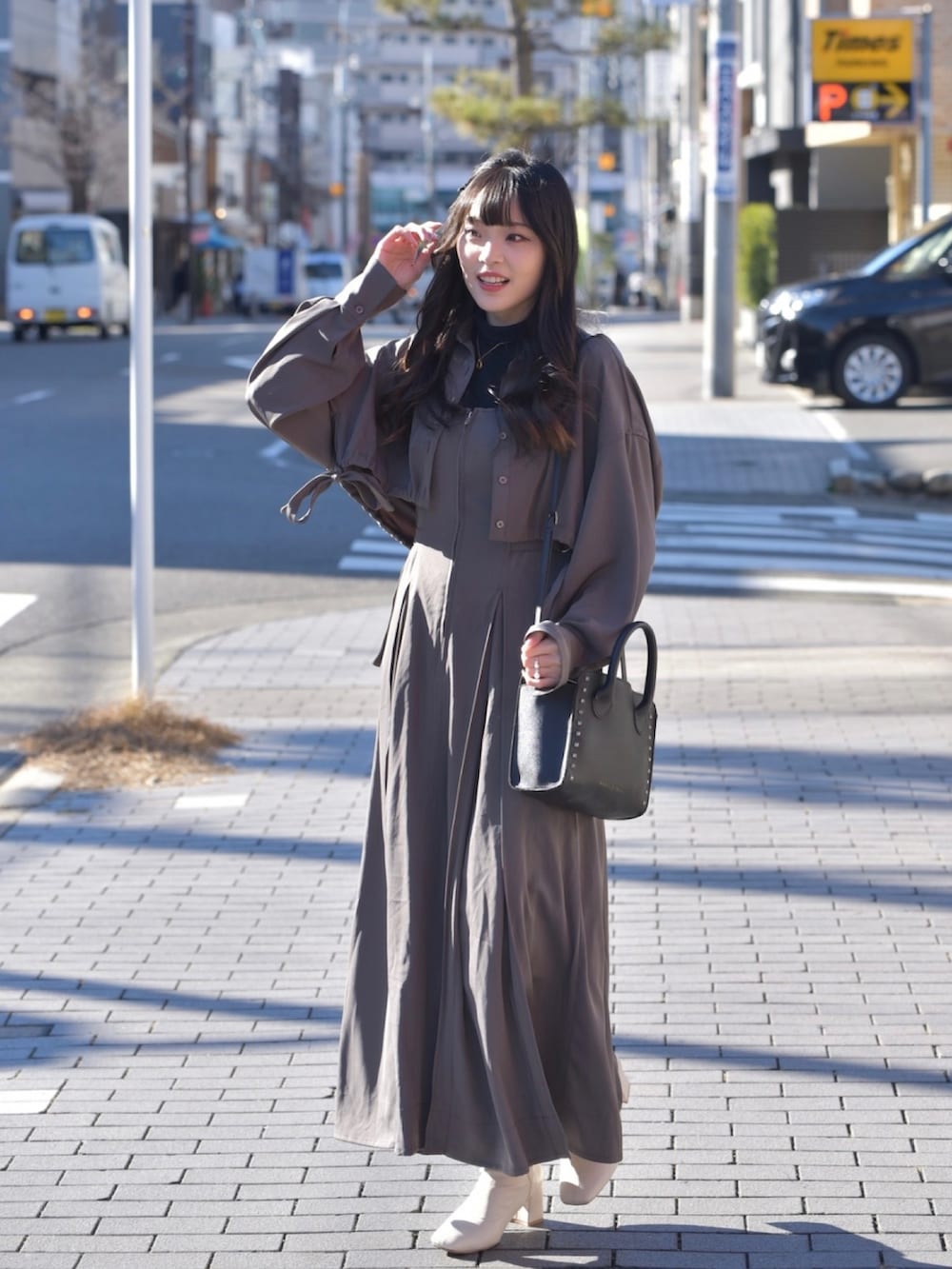 ブラック系のショルダーバッグ、ホワイト系のブーツ、グレー系のワンピースを着用したレディースの冬コーディネートの2枚目の写真