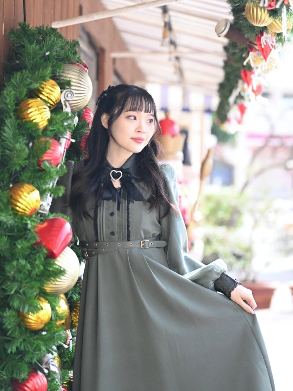 グリーン系のワンピース、ブラック系のブーツを着用したレディースの冬コーディネートの2枚目の写真