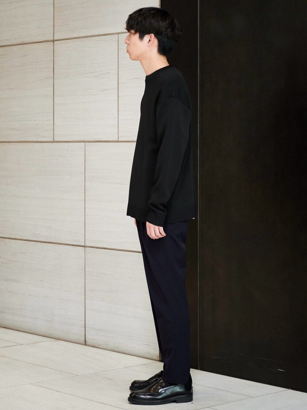 ブラック系のニット/セーター、ブルー系のスラックスを着用したメンズの秋コーディネートの2枚目の写真