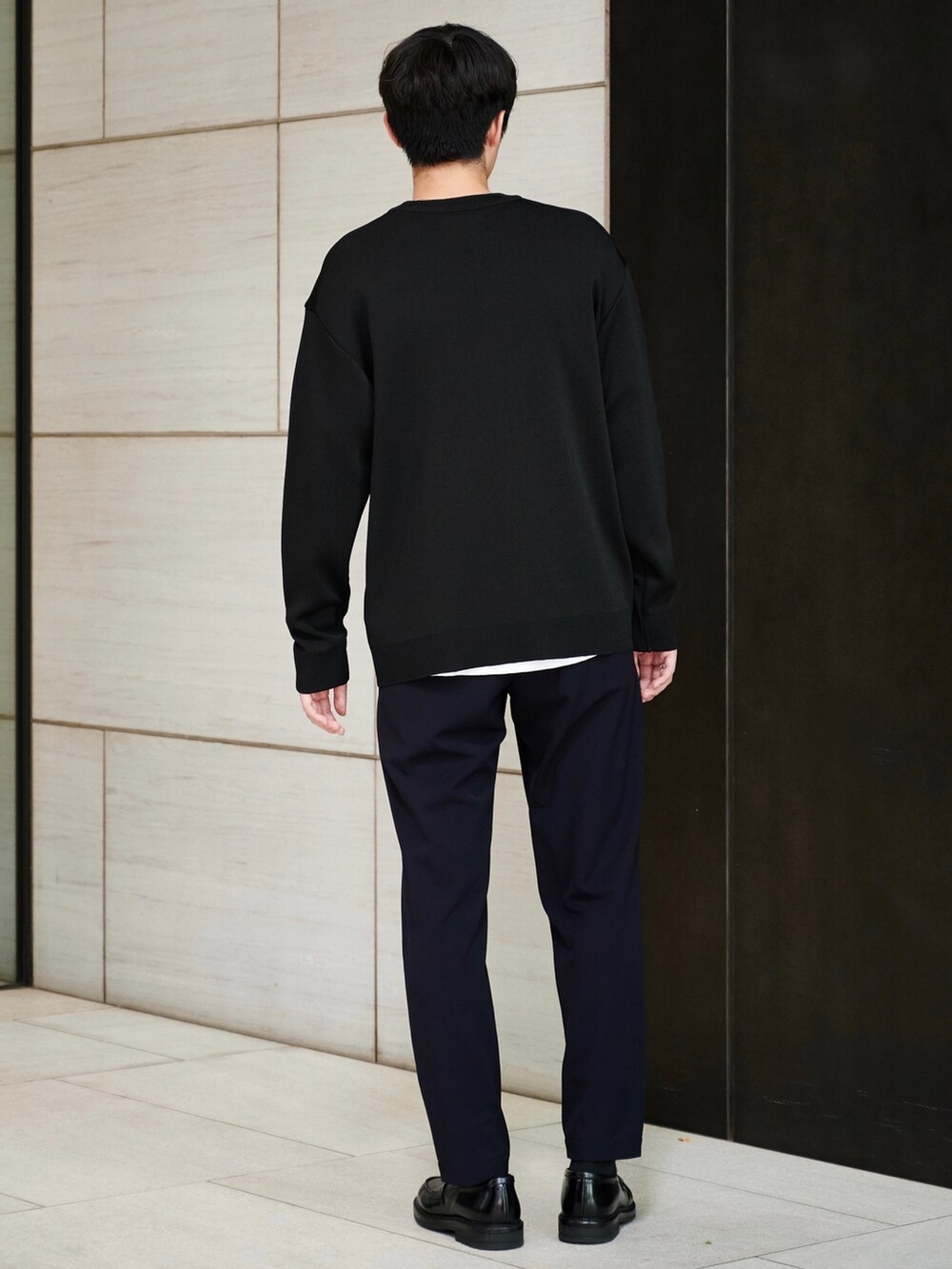 ブラック系のニット/セーター、ブルー系のスラックスを着用したメンズの秋コーディネートの3枚目の写真