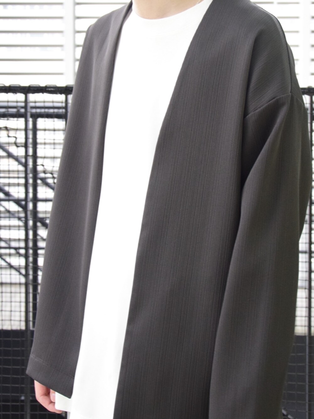 ブラウン系のカーディガン/ボレロ、ホワイト系のスラックスを着用したメンズの春コーディネートの4枚目の写真