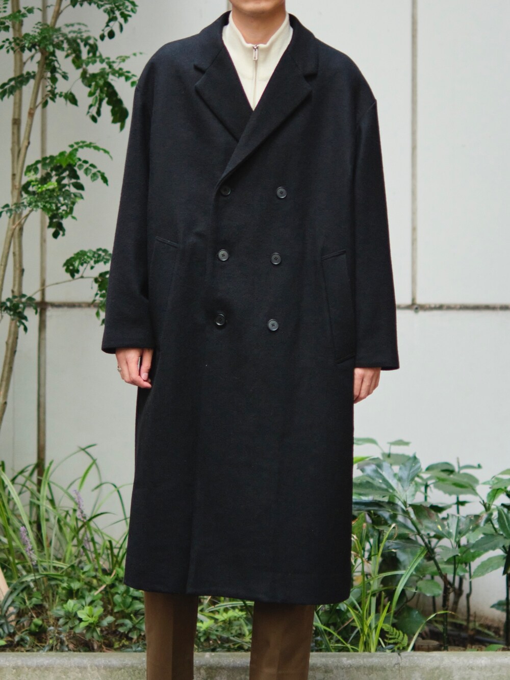 ブラック系のチェスターコートを着用したメンズの秋コーディネートの4枚目の写真