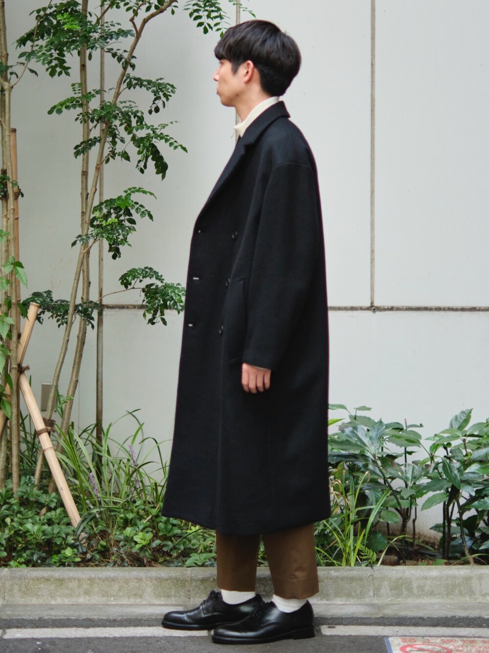 ブラック系のチェスターコートを着用したメンズの秋コーディネートの2枚目の写真