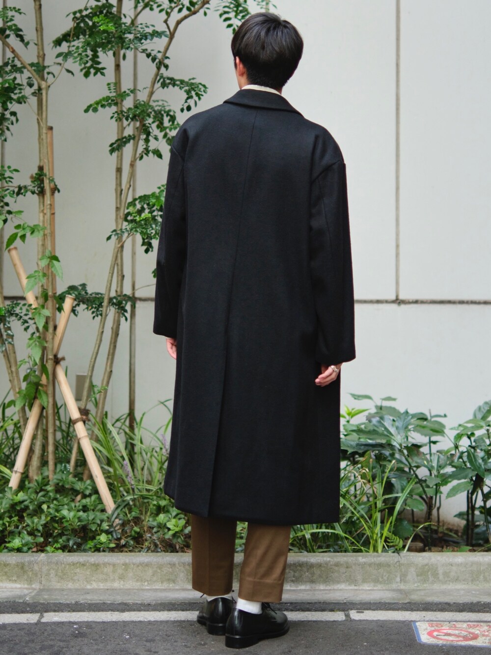 ブラック系のチェスターコートを着用したメンズの秋コーディネートの3枚目の写真