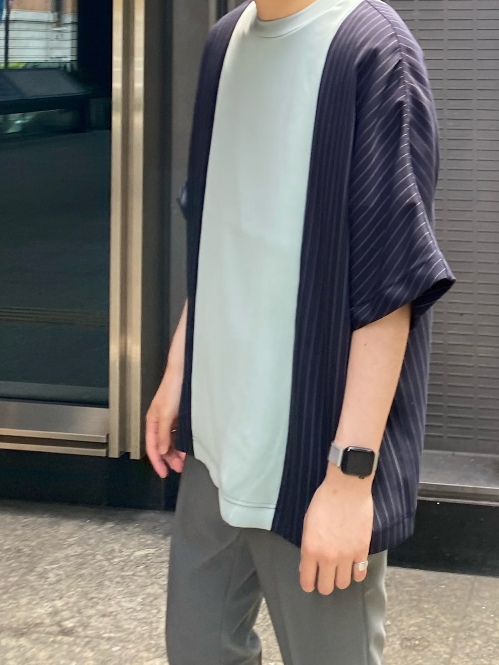 グリーン系のTシャツ/カットソー、グレー系のスラックスを着用したメンズの夏コーディネートの2枚目の写真