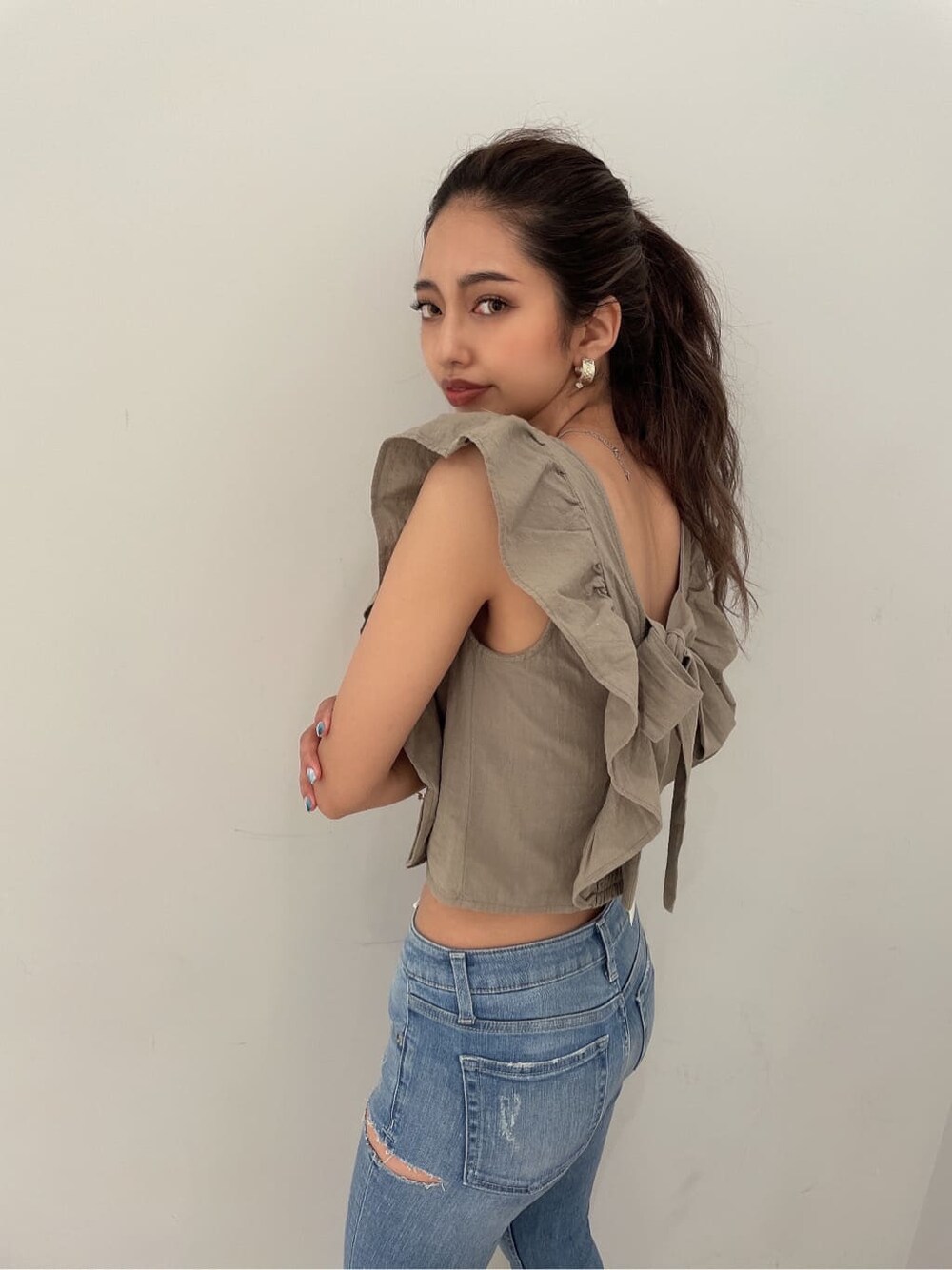 ホワイト系のパンプス、ブルー系のデニムパンツ、ゴールド系のピアス（両耳用）を着用したレディースの夏コーディネートの3枚目の写真