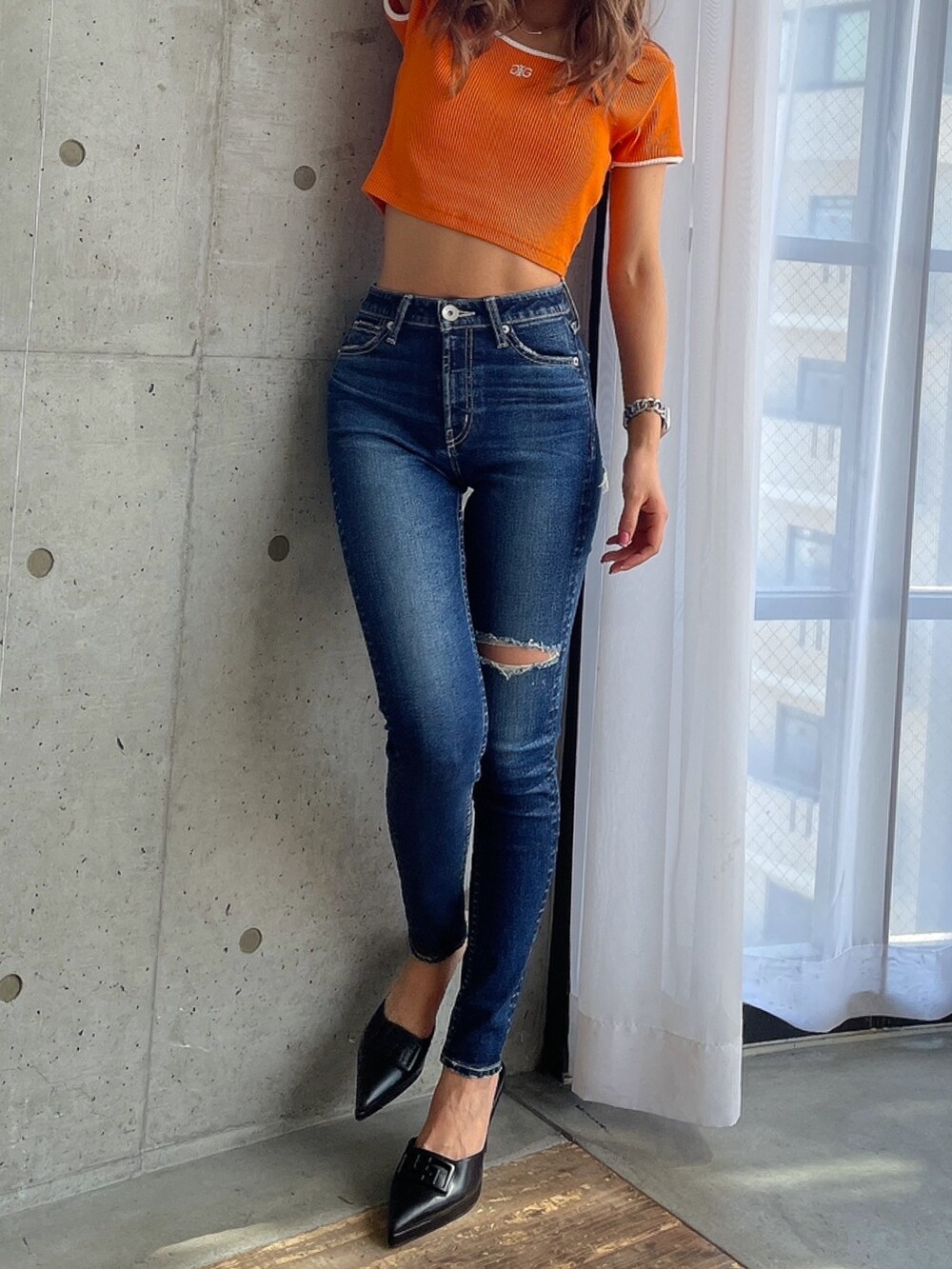 ブルー系のデニムパンツ、オレンジ系のTシャツ/カットソー、ブラック系のパンプスを着用したレディースの春コーディネートの5枚目の写真