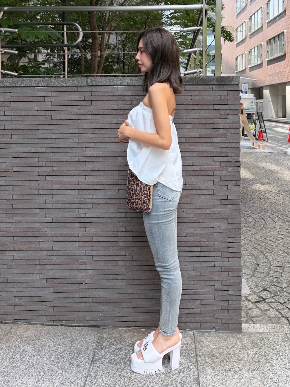 ホワイト系のチューブトップ、その他のショルダーバッグ、ブルー系のデニムパンツを着用したレディースの夏コーディネートの2枚目の写真