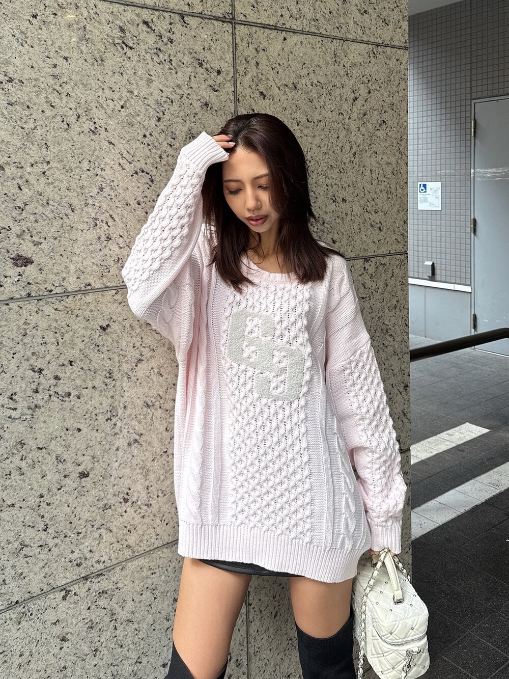 ピンク系のニット/セーター、ブラック系のブーツ、ブラック系のスカートを着用したレディースの秋コーディネートの6枚目の写真