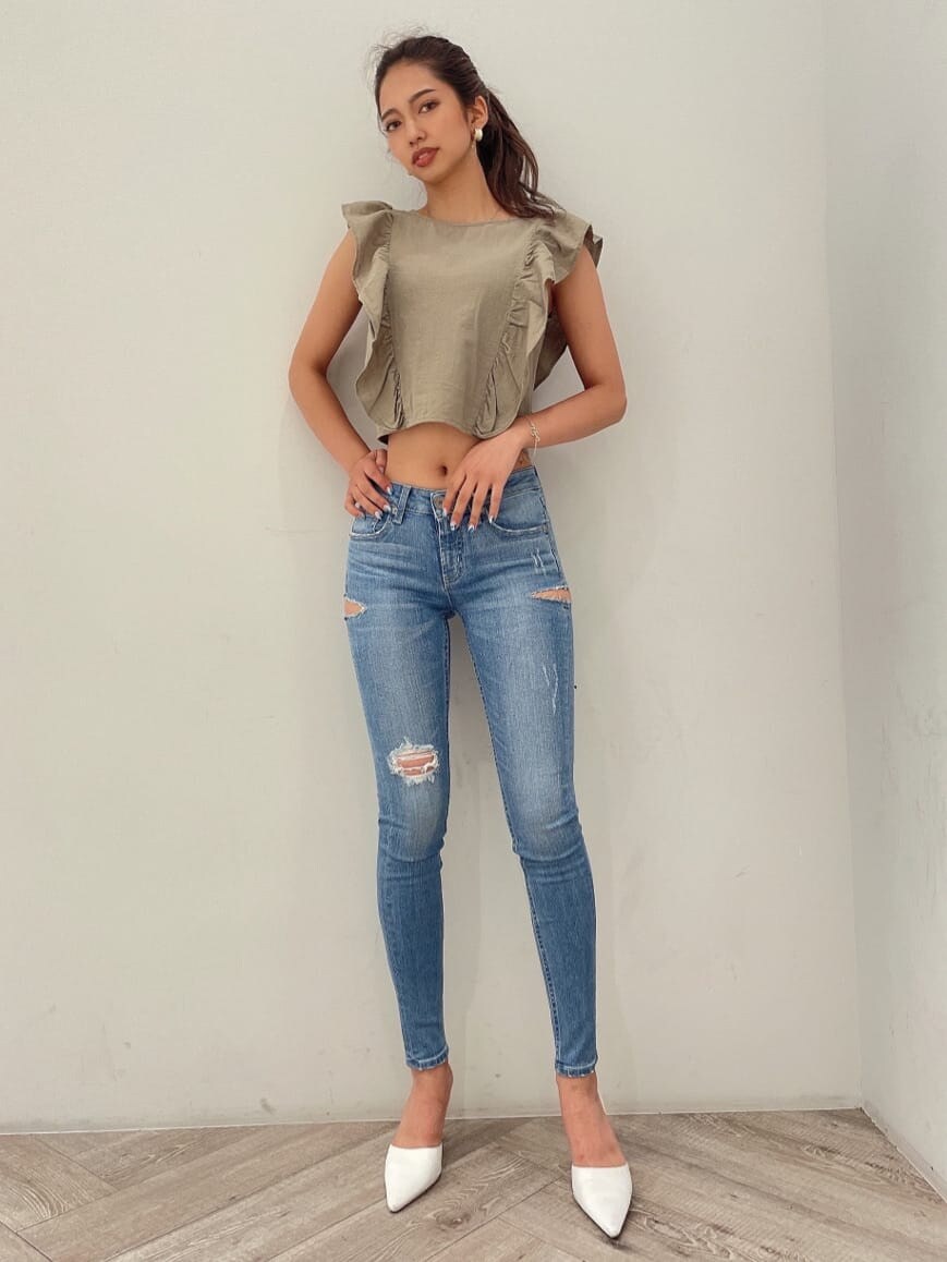 ホワイト系のパンプス、ブルー系のデニムパンツ、ゴールド系のピアス（両耳用）を着用したレディースの夏コーディネートの6枚目の写真