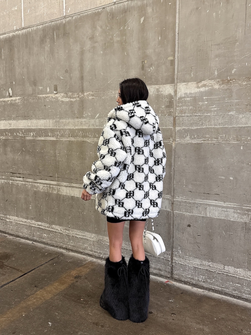 ホワイト系のブルゾン、ブラック系のワンピース、ブラック系のブーツを着用したレディースの秋コーディネートの5枚目の写真