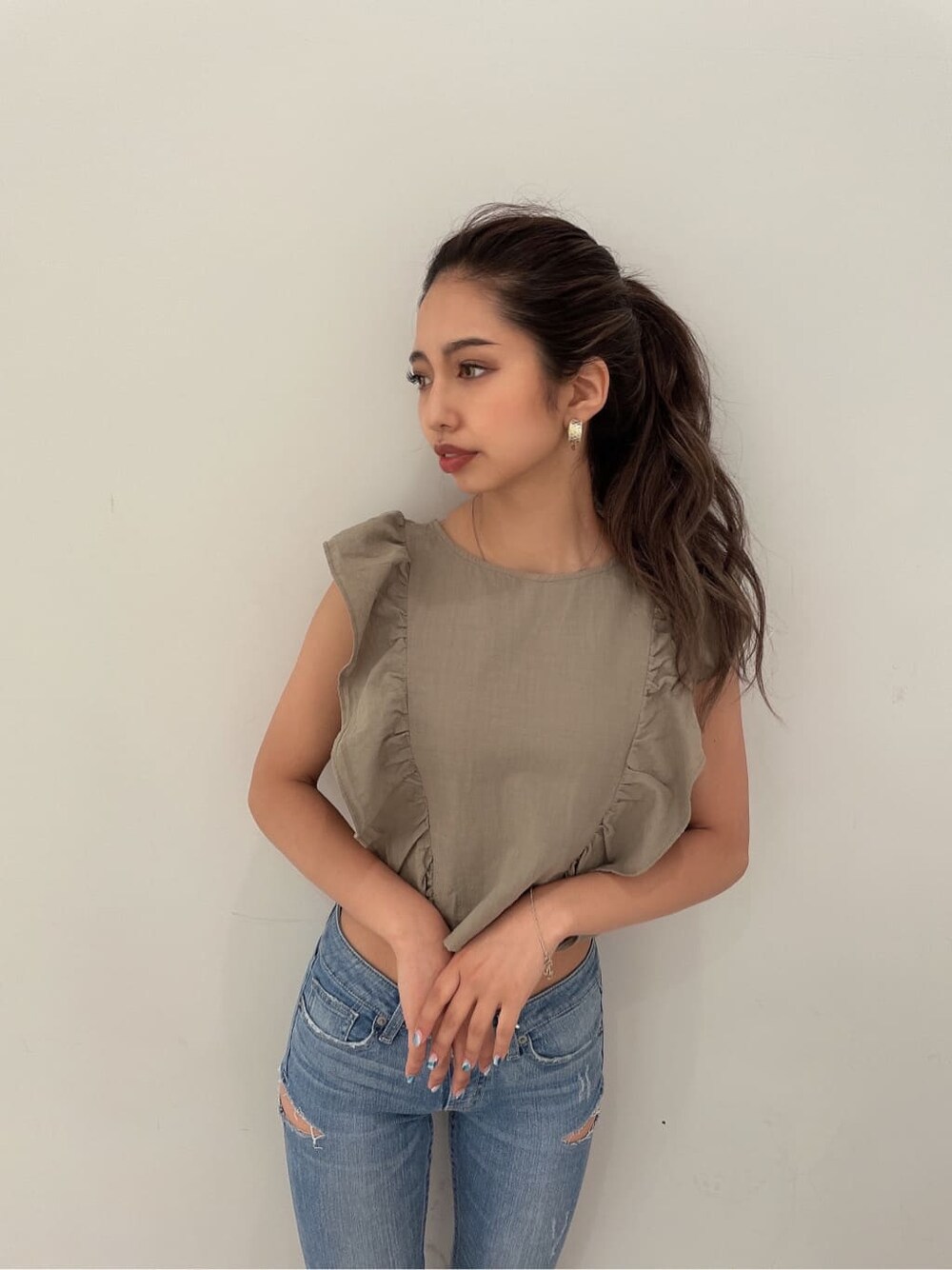 ホワイト系のパンプス、ブルー系のデニムパンツ、ゴールド系のピアス（両耳用）を着用したレディースの夏コーディネートの2枚目の写真