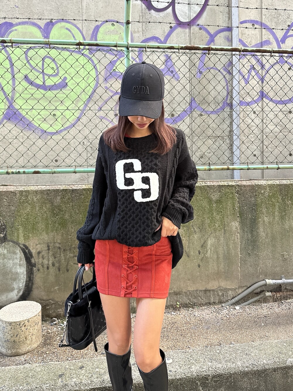 ブラック系のニット/セーター、オレンジ系のワンピース、ブラック系のショルダーバッグを着用したレディースの秋コーディネートの2枚目の写真