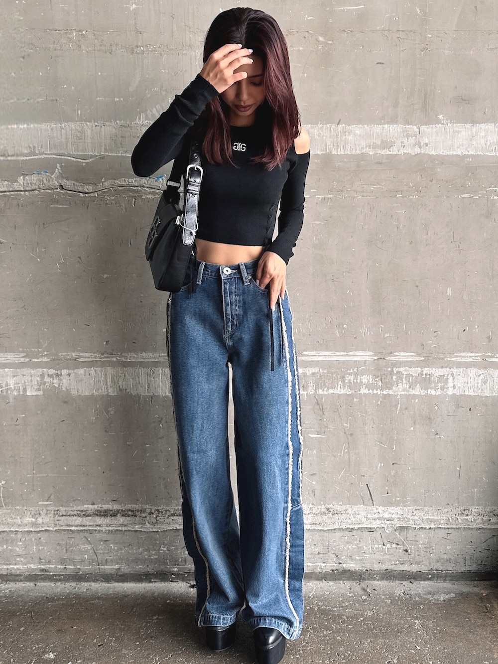 ブルー系のデニムパンツ、ブラック系のニット/セーター、ブラック系のハンドバッグを着用したレディースの秋コーディネートの5枚目の写真